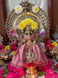 a small statue sitting on top of a table filled with flowers