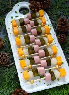 an appetizer platter with pickles and cheeses on skewers