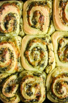 a pan filled with rolls covered in pesto and cheese