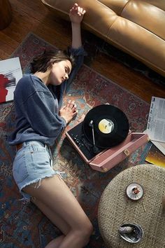 a woman laying on the floor next to a record player