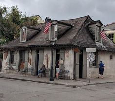 people are standing outside of an old building with american flags on the roof and windows