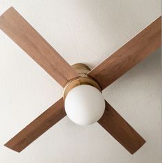 a ceiling fan mounted on the wall with a white ball hanging from it's wooden blades