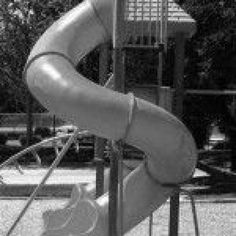 a black and white photo of a child's play area with a slide in the background