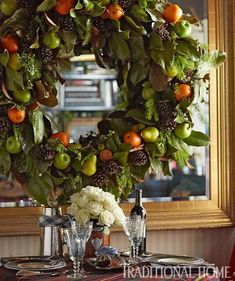 a table with a wreath on top of it next to wine glasses and silverware