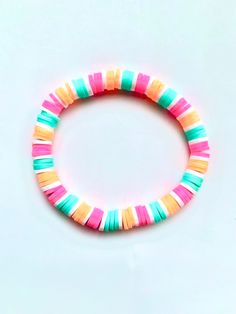 a bracelet made out of multicolored plastic beads on a white surface with a black bead in the middle