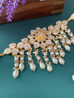 Pachi kundan with mother of pearl (Mop) . Happy design worn flower details . Comes with matching earring and Tikka . About 2 inch wide on the neck . Earring is about 2.25 inch . Push back , completely gold plated ,Hypoallergenic. Tikka included. White Kundan Chandbali Pearl Necklace, White Pearl Kundan Chandbali Necklace, White Kundan Necklace With Mirror Work, White Bridal Necklace With Mirror Work For Diwali, White Pearl Chandbali Kundan Necklace, White Kundan Necklace With Mirror Work For Diwali, Heavy White Kundan Necklace With Pearls, White Pearl Kundan Necklace For Diwali, White Kundan Choker Necklace In Temple Jewelry Style