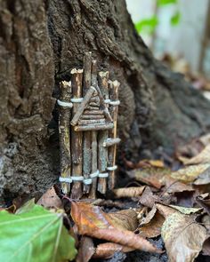 a wooden sculpture sitting on the ground next to a tree