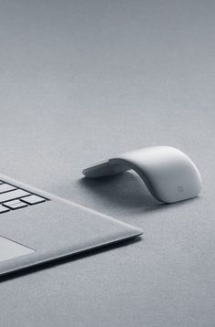 a computer mouse sitting on top of a white laptop keyboard next to an apple macbook pro