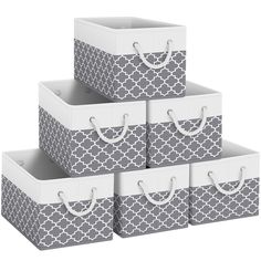 four gray and white storage bins with handles on each side, one in the shape of a trellis pattern