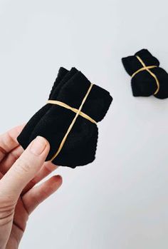 someone is holding two pairs of black cloth napkins with gold crosses on the sides