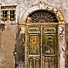 an old building with two wooden doors and one has a window on the outside wall