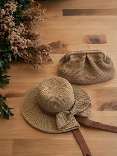 two hats sitting on top of a wooden floor next to a bouquet of wildflowers