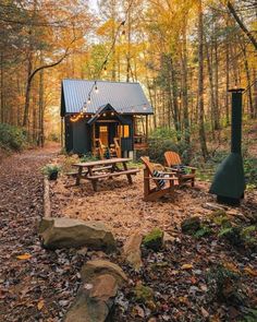 a small cabin in the woods with picnic tables and firepits on the ground