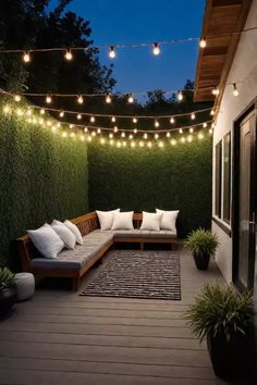 an outdoor seating area with lights strung over the wall and potted plants on the deck