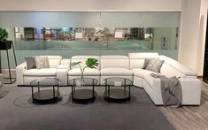 a white sectional couch sitting in front of a glass table on top of a rug