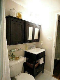 a white toilet sitting next to a sink in a bathroom under a vanity with two mirrors