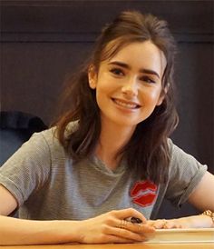 a young woman sitting at a table with a cell phone in her hand and smiling