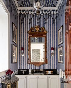 a bathroom with blue and white wallpaper has a mirror on the cabinet above it