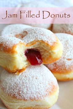 jam filled doughnuts on a plate with powdered sugar and jelly in the middle