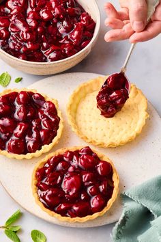 three pies with cherries on them and one being dipped with a spoon