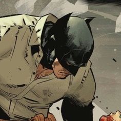 a man in a batman costume kneeling down with his head on the ground and hands over his face