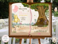 an open book with winnie the pooh's first birthday on it and balloons