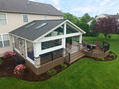 a house with a deck and patio in the middle of some green lawning area