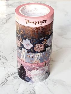 three rolls of washi tape sitting on top of a marble counter with floral designs