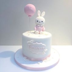 a white cake with pink frosting and a bunny on top that says boyahe