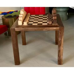 a wooden chess set sitting on top of a table next to a red chair in a room