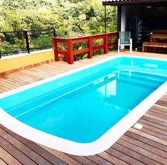 an above ground swimming pool with decking and railings on the outside, surrounded by trees