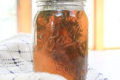 a mason jar filled with fresh herbs on top of a blue and white table cloth