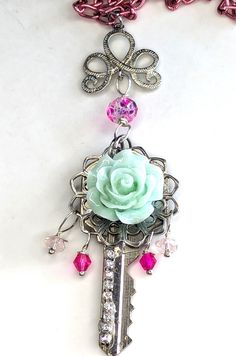 a key with a rose on it is attached to a chain that also has charms