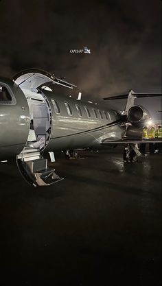 an airplane sitting on the tarmac at night with its door open and lights on