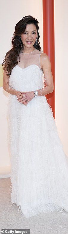 a woman in a white dress posing for the camera with her hands on her hips