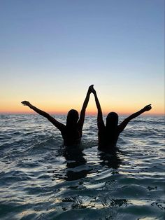 two people in the water with their arms up