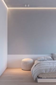 a white bed sitting under a ceiling light in a bedroom next to a wooden floor