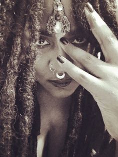 a woman with dreadlocks holding her hands to her face and looking at the camera