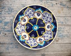 a blue and white plate sitting on top of a wooden table next to a wall