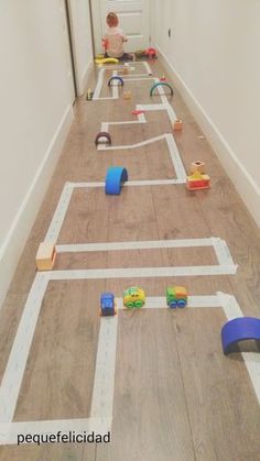 two children playing with toys on the floor in an empty room, while another child watches