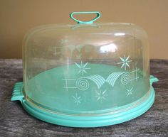 a glass covered cake dish sitting on top of a wooden table