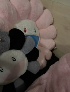 a pile of stuffed animals sitting next to each other on a wooden table with pink sheets