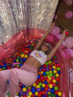 a woman laying on top of a pink ball pit filled with lots of colorful balls