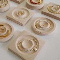 several rings and bracelets are on display in wooden trays with bead caps