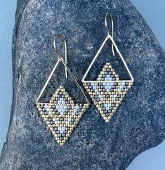 a pair of earrings sitting on top of a rock next to a blue and white stone