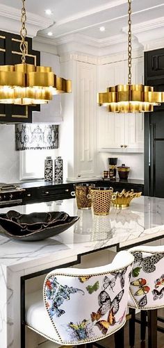 a large kitchen with black cabinets and white counter tops, gold chandelier hanging from the ceiling