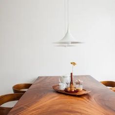 a wooden table with plates and cups on it in front of a light fixture hanging from the ceiling