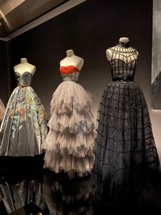 three dresses are on display in a museum