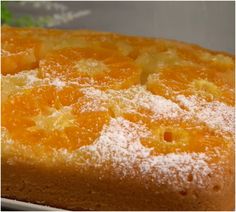 an orange cake with powdered sugar on top sits in a pan, ready to be eaten