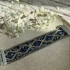 a blue beaded belt sitting on top of a table next to a vase with flowers